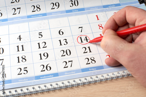 hand marks date on the calendar in red
