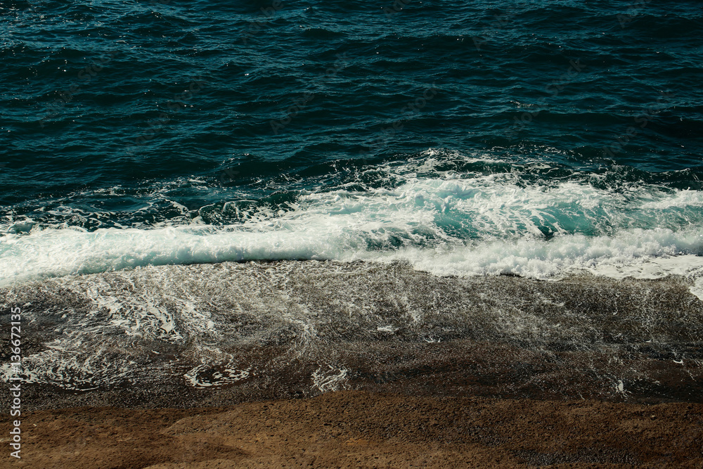 Fototapeta premium Beautiful aquamarine sea waves crash against brown stones