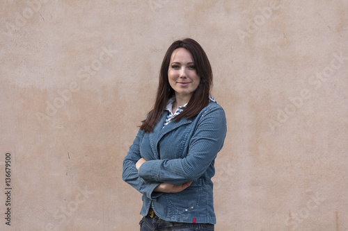 Beautiful woman in a blue jacket on the background wall. People