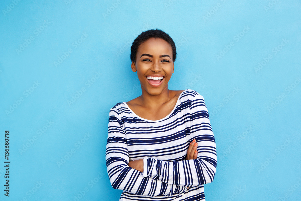 happy young black woman laughing against blue wall happy young black woman laughing against blue wall