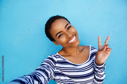 cool young black woman taking selfie with peace hand sign