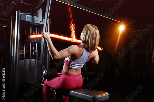 Young fitness woman doing exercises the major muscle groups in the gym. Strength training. Fiery training machine.