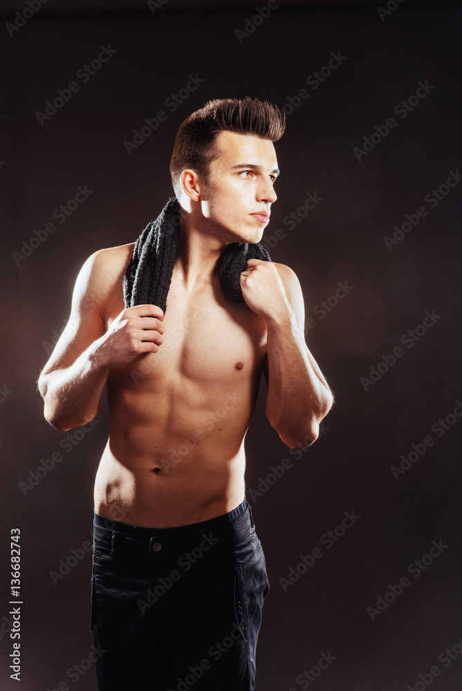 Sexy young man with a naked torso on dark background .
