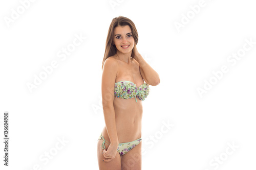 happy young woman with big natural breast in swimsuit with floral pattern looking at the camera and smiling isolated on white background