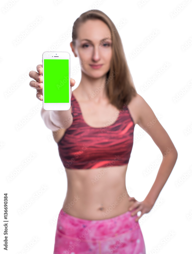 Happy smiling fitness girl showing chromakey smartphone screen in studio. Isolated over white background.