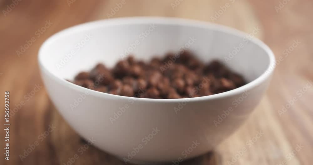 chocolate cereal balls with milk in white bowl on wood table slide movement, 4k prores footage chocolate cereal balls with milk in white bowl on wood table slide movement, 4k prores footage