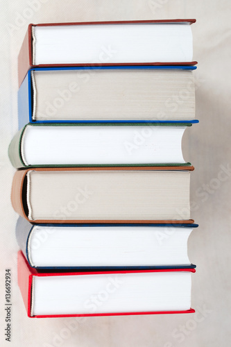 Stack of hardback books on table. Top view.