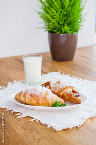 Served breakfast with assortment of fresh pastries and glass of milk on the wooden table. Selective focus photo