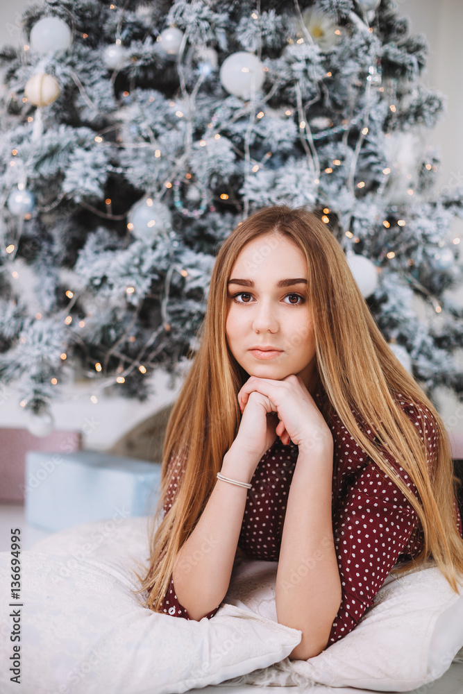 Christmas Gift. New year celebration. Beautiful holiday decorated room with Christmas tree with presents under it. New Year and Christmas concepts. Beautiful girl sitting near New Year tree. Christmas Gift. New year celebration. Beautiful holiday decorated room with Christmas tree with presents under it. New Year and Christmas concepts. Beautiful girl sitting near New Year tree.