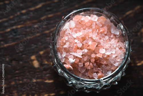 Pink salt in a bowl on a wooden table on the right