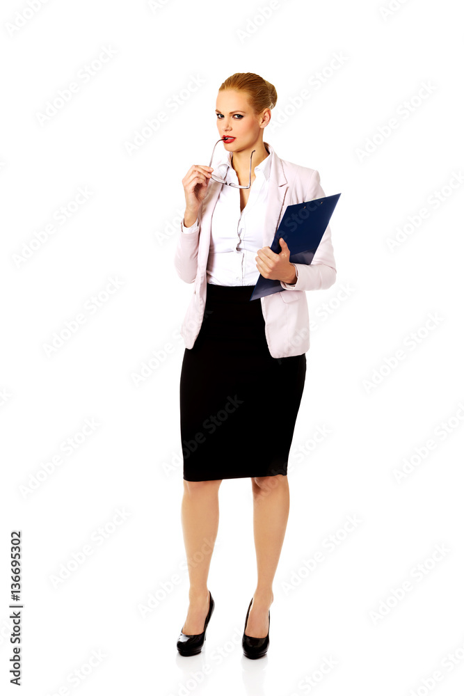 Pensive business woman holding a clipboard and glasses Pensive business woman holding a clipboard and glasses