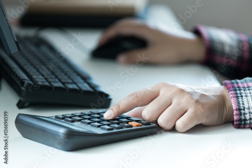 Woman's hands using calculator on table