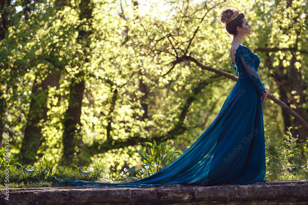 Beauty woman in green luxury expensive dress and in crown on the nature. Beautiful model girl in a green wedding dress. Female portrait in the park. Woman with hairstyle. Cute lady outdoors Beauty woman in green luxury expensive dress and in crown on the nature. Beautiful model girl in a green wedding dress. Female portrait in the park. Woman with hairstyle. Cute lady outdoors