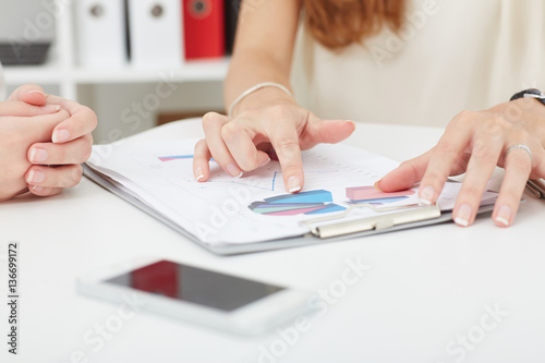 Group of business people looking at the clipboard with graphics.