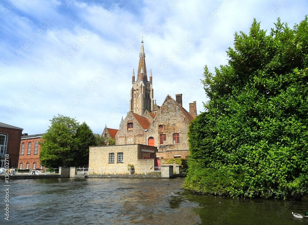 Church and vintage building as seen from cruising boat, Bruges, Belgium 