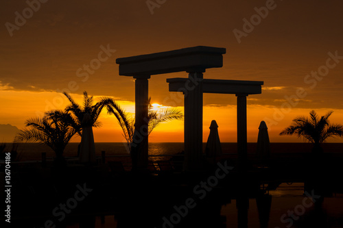 Sonnenuntergang am Pool mit Palmen und Säulen