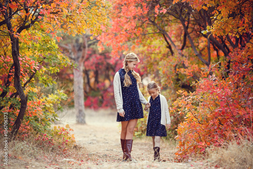 Fotografie Two cheerful sisters playing in the park in warm autumn day