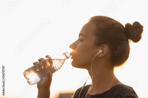 Selective focus Sports girl drinks water during a workout on the beach. The girl drinks water during fitness outdoors