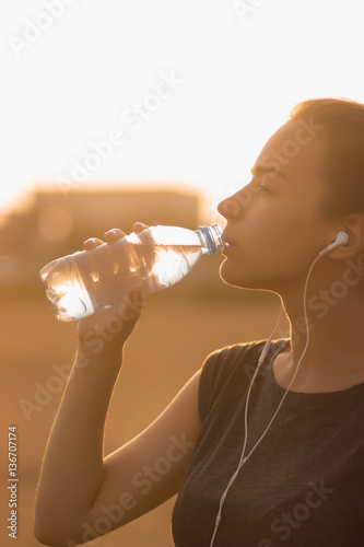 Selective focus Sports girl drinks water during a workout on the beach. The girl drinks water during fitness outdoors