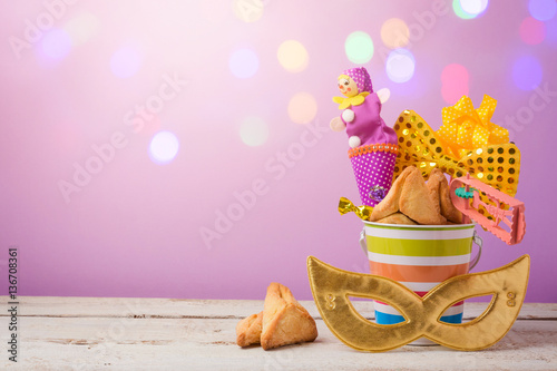 Purim holiday concept with carnival mask and gifts over bokeh lights background photo