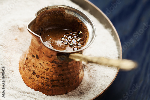 Turkish coffee made in cezve (traditional coffee pot) on sand photo