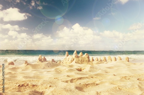 Dreamy Sand castle built on seashore, ocean background. Soft retro warm toned, pastel colors, lens flare effect. 