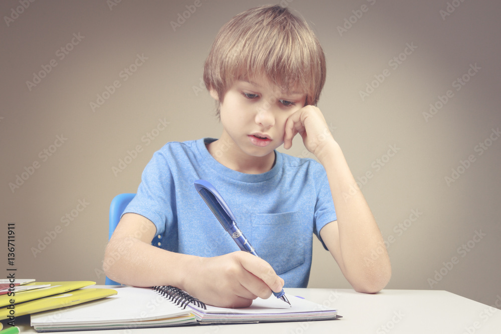 Boy writing on paper notebook. Boy doing his homework exercises Boy writing on paper notebook. Boy doing his homework exercises