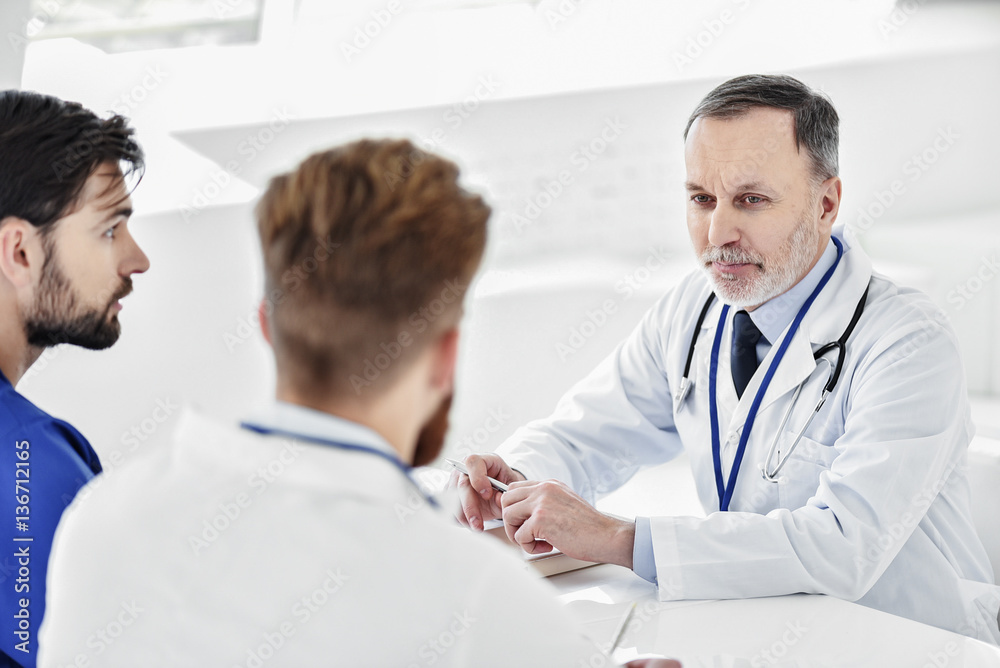 Curious doctors speaking at round table Curious doctors speaking at round table