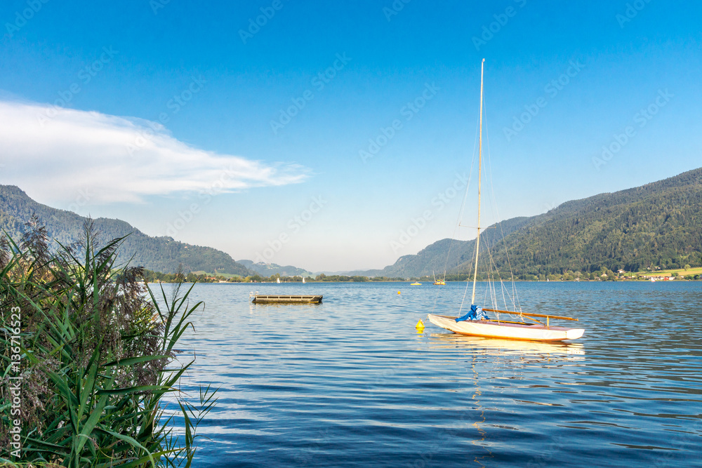 Naklejka premium Segelboot am nahen Schilfufer auf dem Ossiacher See