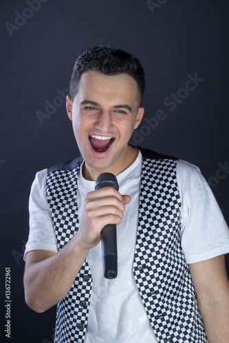 Young male black-haired rock vocalist performs singing to microp photo