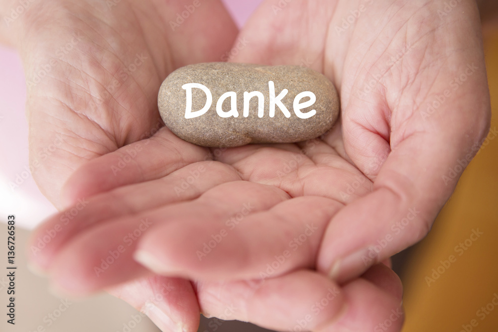 womans hands holding a stone with german word for Thank You womans hands holding a stone with german word for Thank You