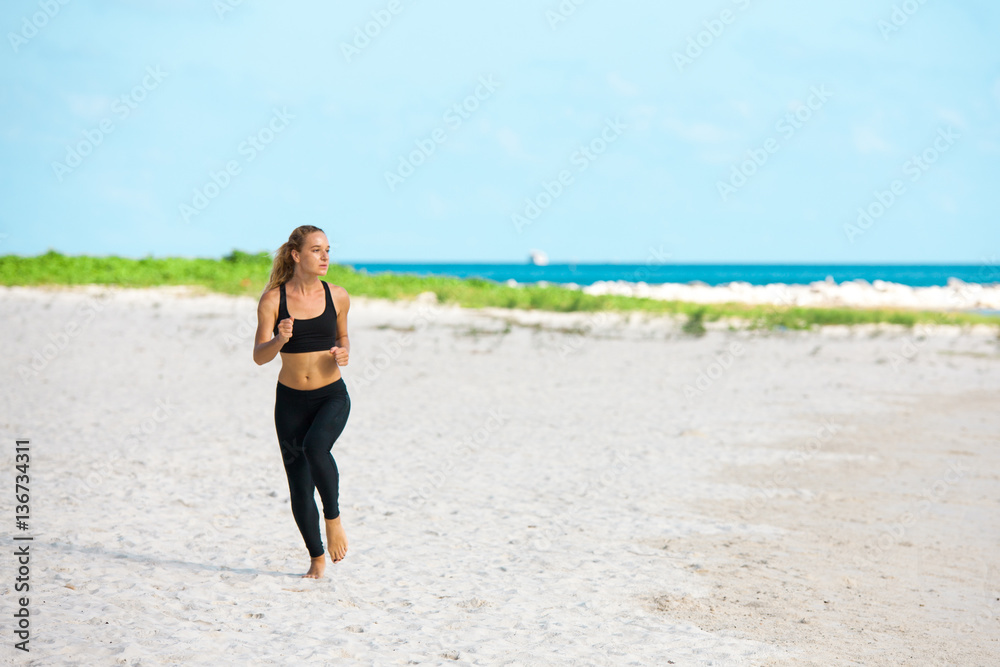 young fitness woman running at beach