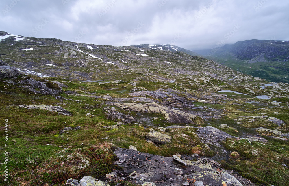 The rough terrain with water from melted snow, moss, exposed granite and low hanging clouds, on the way to Stordalsnibba