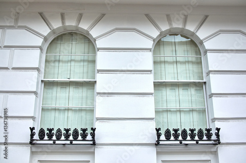 Fotografie Two arched window recessed in white ashlar walling building facade, with an iron