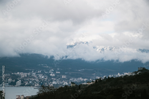 Beautiful views of the city near the sea covered with clouds from the mountains