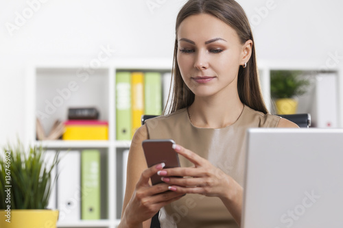 Woman in beige looking at phone screen