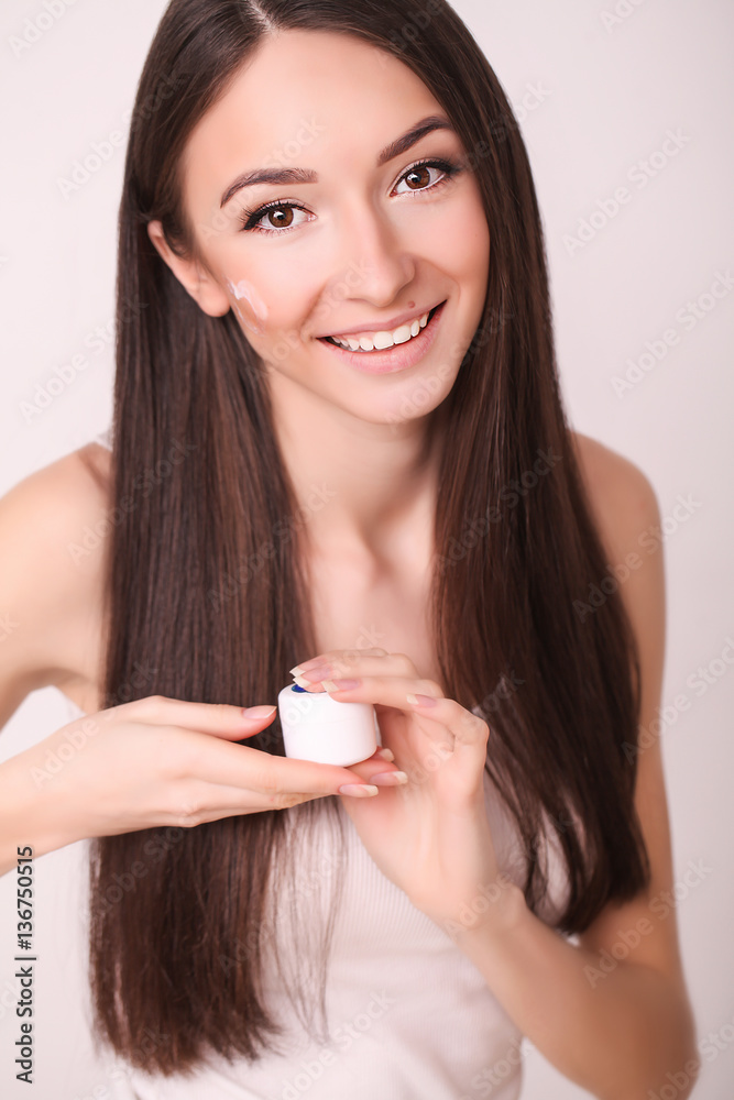 beauty, people, cosmetics, skincare and health concept - happy smiling young woman applying cream to her face beauty, people, cosmetics, skincare and health concept - happy smiling young woman applying cream to her face