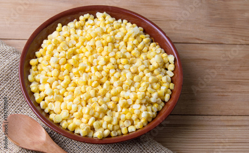 Bowl of frozen corn with a wooden spoon