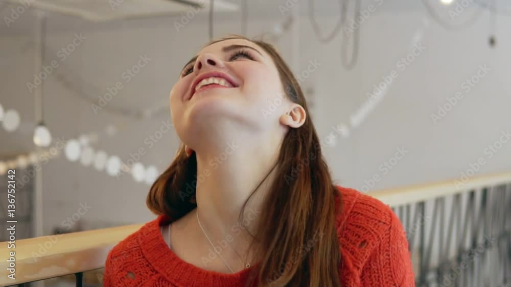 A cute young woman smiles at the camera on coffe-shop background close up A cute young woman smiles at the camera on coffe-shop background close up