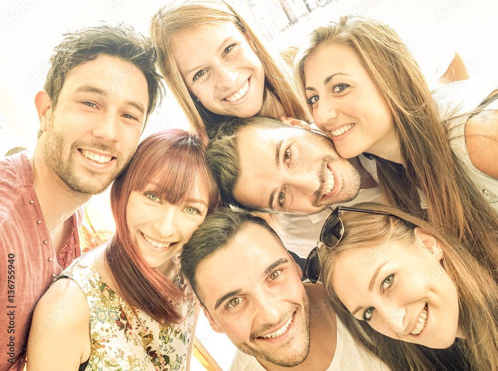 Happy best friends taking selfie outdoors with spring time backlighting - Friendship and happiness concept with young people having fun together - Warm vintage filter with bright sunshine color tones