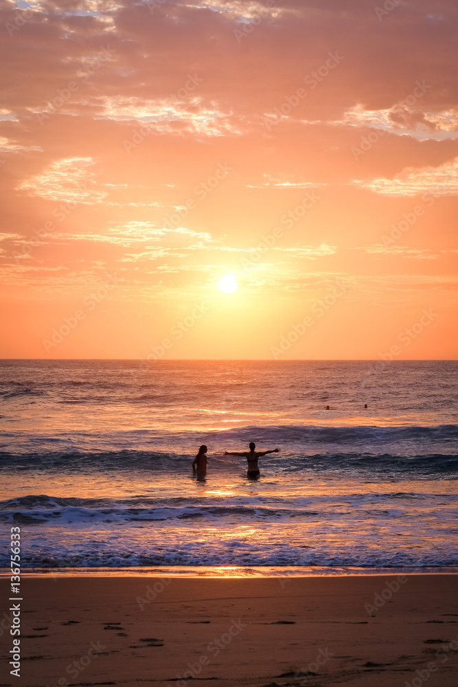 Two women in the water at the beach at sunrise