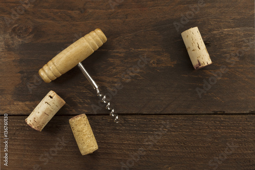 Photo of wine corkscrew and corks on dark background