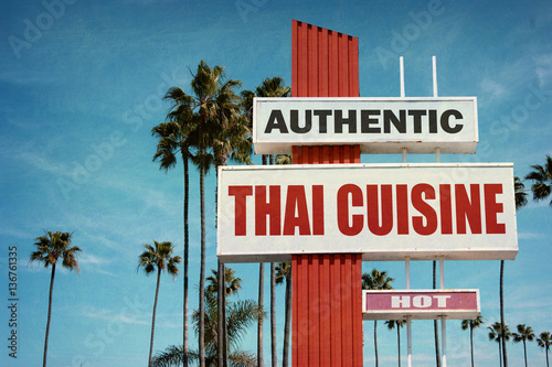 aged and worn vintage photo of thai cuisine sign with palm trees