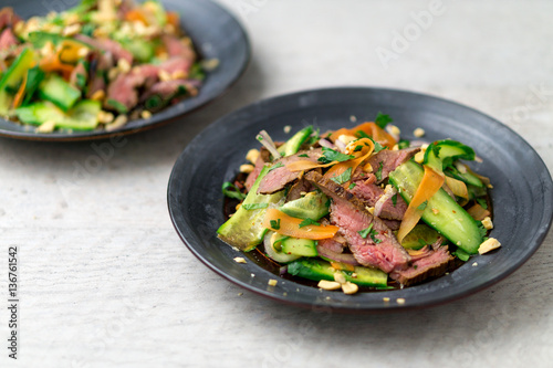 Angled view of healthy asian beef salad. Inspired by Thai and Vietnamese cuisine, this salad is made with fresh vegetables (carrots, onions, cucumber, etc) and a nicely seared flank steak