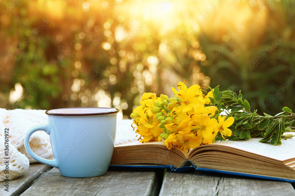 Fototapeta premium old book, cup of coffee next to field flowers