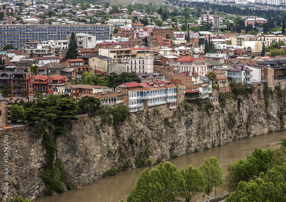 Georgia, Tbilisi. View from the fortress Narikala on Avlabari./Georgia, Tbilisi. View from the fortress Narikala on Avlabari district , houses on a cliff , leaving the water in the Kura River .