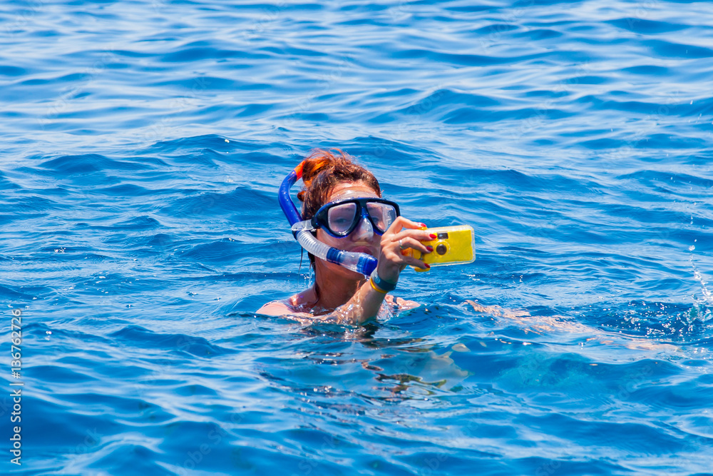 happy woman wearing a mask in the sea, along with a camera