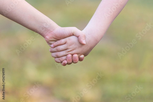 Kids' hands holding for support and friendship, outdoor with blu © kudosstudio