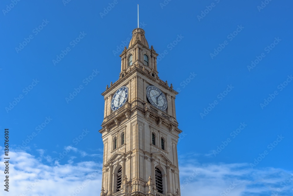 The clock tower of the Melbourne GPO building against a blue sky with light cloud cover