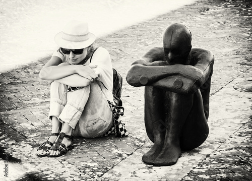 Young woman sits and imitates the pose of the statue, colorless photo